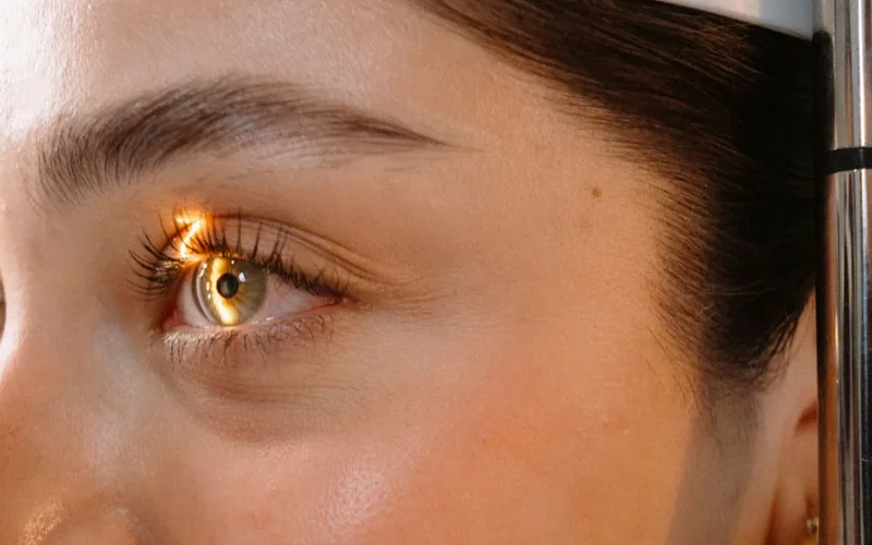 Paciente apoiada na lâmpada de fenda durante o exame dos olhos