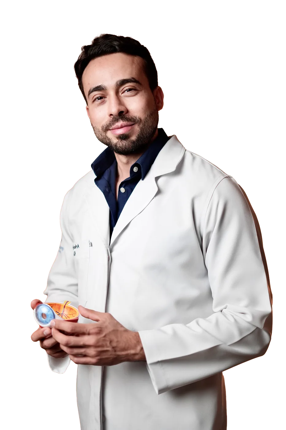 Dr. Arthur Berrêdo, oftalmologista, de jaleco branco segurando um modelo de olho